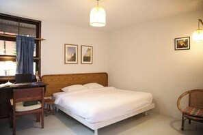 Un dormitorio con cama, un escritorio con silla y una ventana con cortinas.