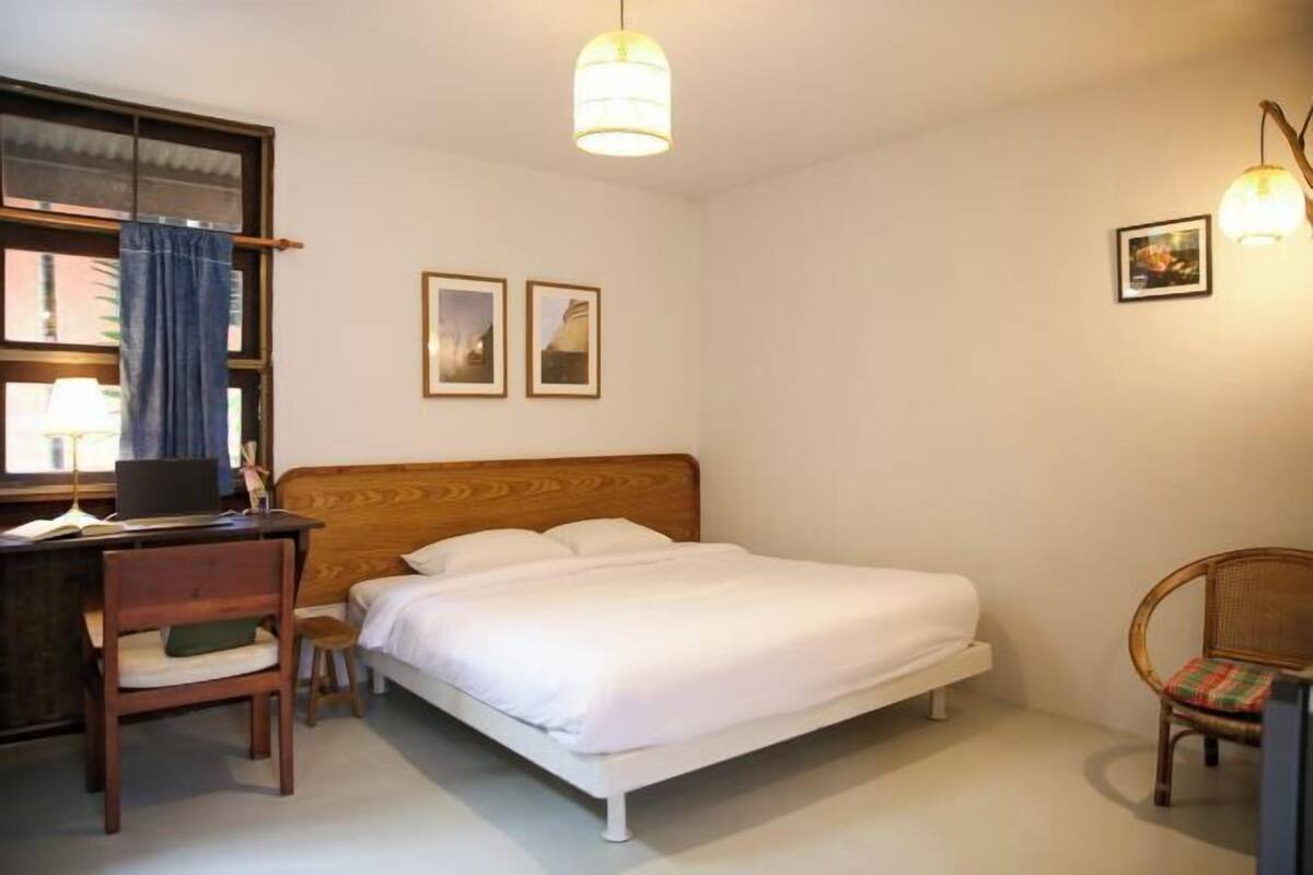 Une chambre à coucher comprenant un lit, un bureau, une chaise et un luminaire suspendu.