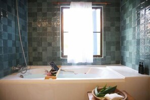 Un baño con bañera, ventana y zona de ducha.