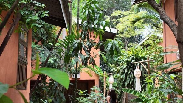 A courtyard with a building, lush greenery, and a hanging light fixture. - Baannoi Retreat and Stay Chiang Mai (Chiang Mai)