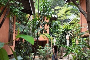 A courtyard with a building, lush greenery, and a hanging light fixture. - Baannoi Retreat and Stay Chiang Mai (Chiang Mai)