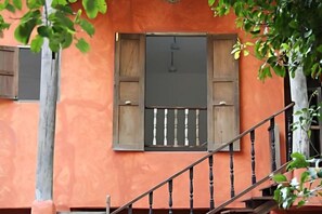Un edificio con una escalera y un ventanal con contraventanas de madera.