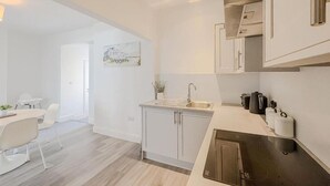 Et moderne køkken med hvide skabe, en rustfri stålvask og en sort bordplade.