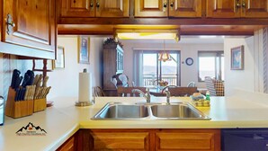 Una cucina con mobili in legno, un lavello a due vasche e una zona pranzo con tavolo e sedie.