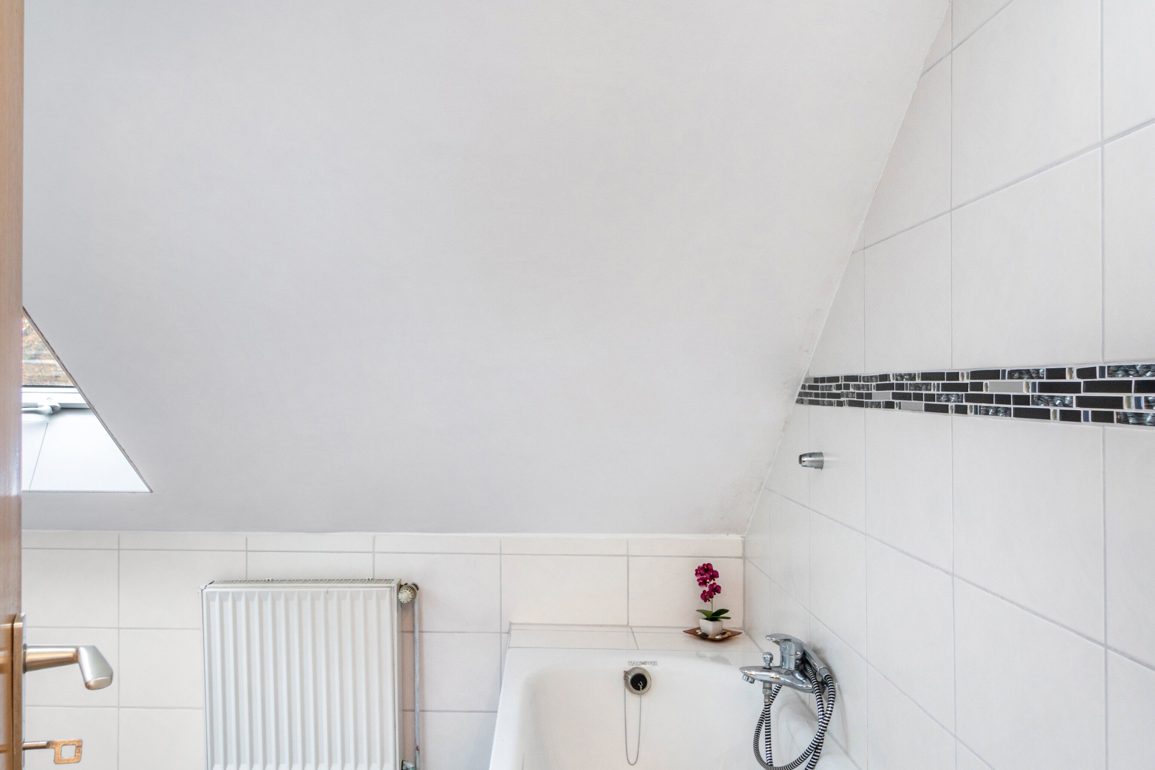 Une salle de bain moderne équipée d’une baignoire, d’une douche et d’un radiateur.