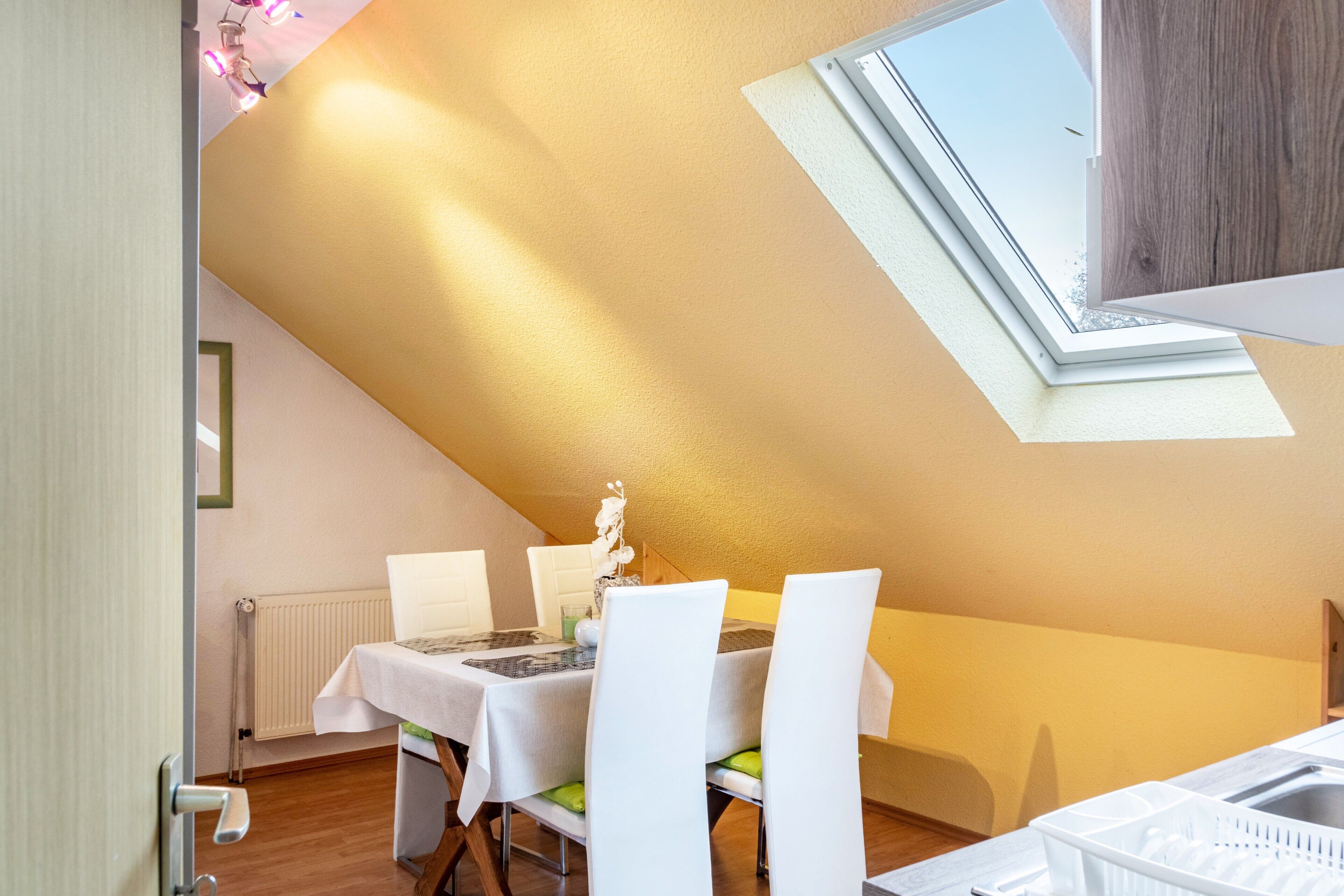 A dining area with a table set for four, a radiator, and a skylight.