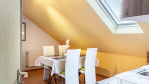 Een eetgedeelte met een tafel voor vier personen, een radiator en een dakraam.