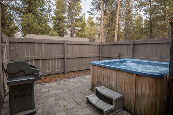 Ein Garten mit Whirlpool, Grill und einer Holzterrasse.