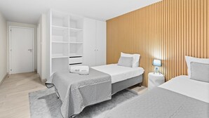 A modern bedroom with two beds, a wardrobe, and a bedside table with a lamp. - GuestReady - Charming Porto's nook (Porto)