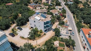 An aerial view of a residential area with a modern two-story house featuring a curved balcony and solar panels. - Sun George (Himare)