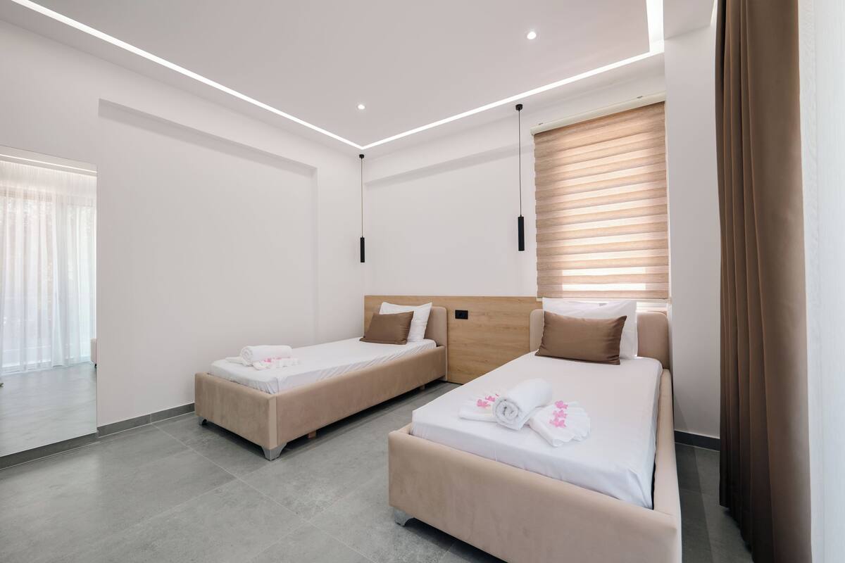 Habitación de hotel moderna con dos camas, un espejo grande y vistas a la ciudad.