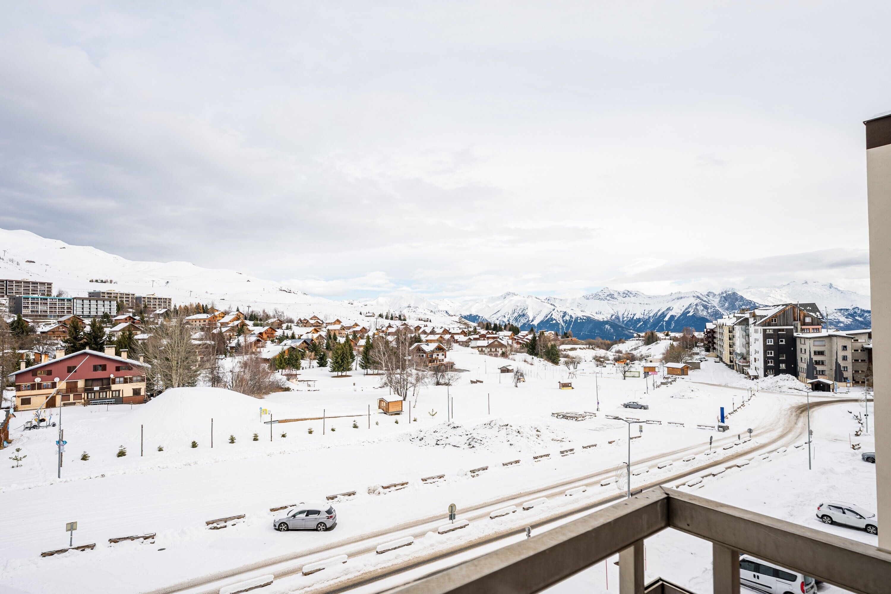 A snowy mountain town with buildings, a road, and a view of snow-covered mountains.