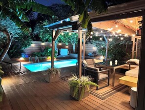 A wooden deck with a pool, outdoor furniture, and string lights. - Spacious 3BR Home in Heart of NOLA with Heated POOL (New Orleans)