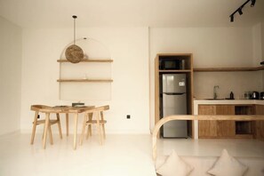 Een moderne keuken met houten kastjes, een inbouwkoelkast en een eethoek met een houten tafel en stoelen.