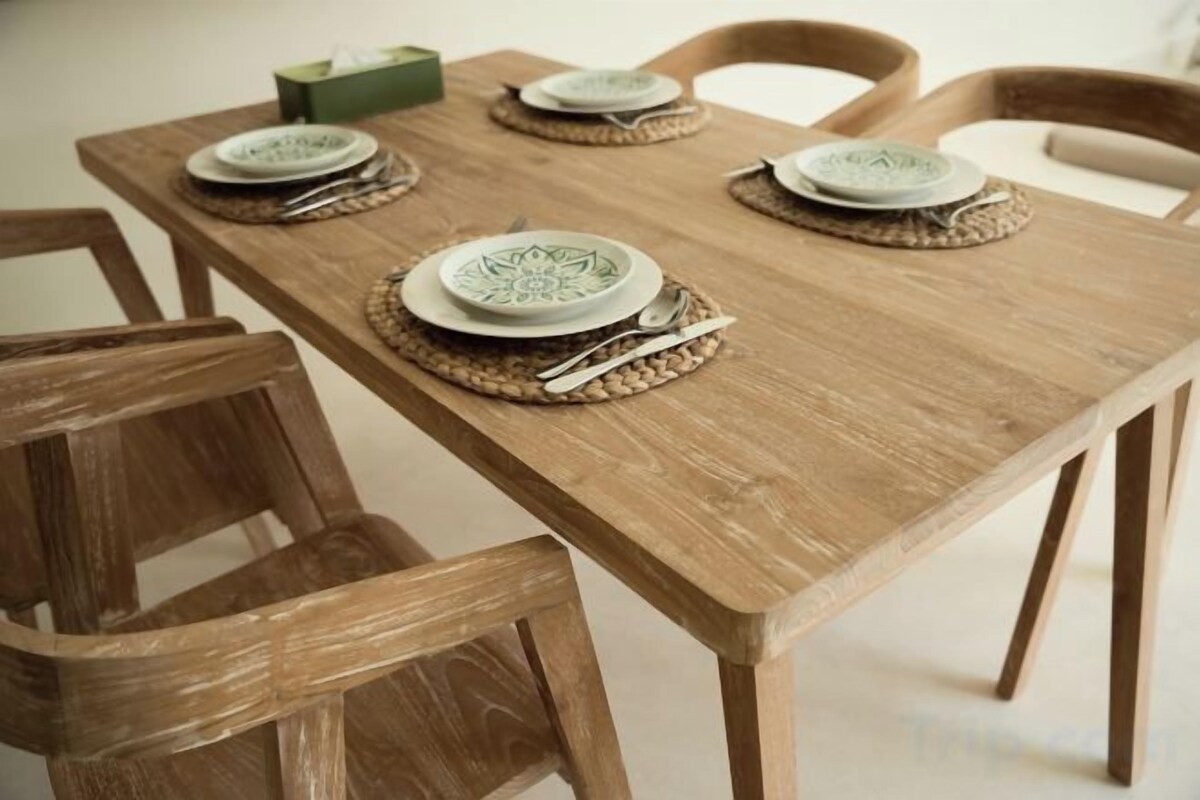 Een houten eettafel gedekt met borden, bestek en placematen.