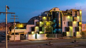 Un edificio moderno de varios pisos con un diseño arquitectónico único, que cuenta con balcones y amplias ventanas.