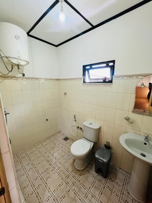 Et lille badeværelse med toilet, vask og brusebad.