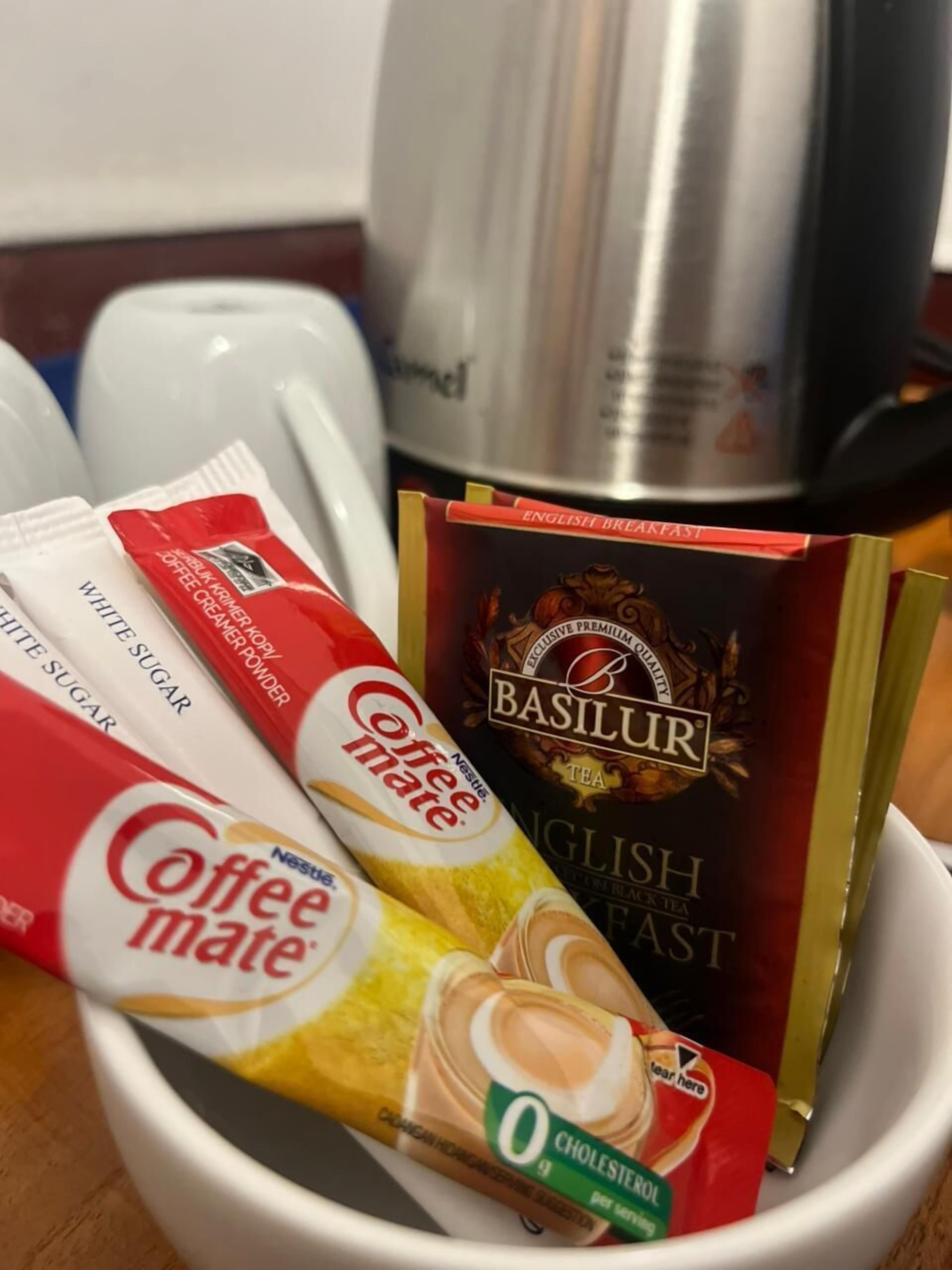 Een koffiezetapparaat, een doos English Breakfast thee, en zakjes koffiemelk en suiker.