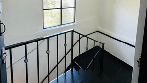 A room with a window, a staircase, and a ceiling with a grid pattern. - The Crowns Lodge (Nuwara Eliya)