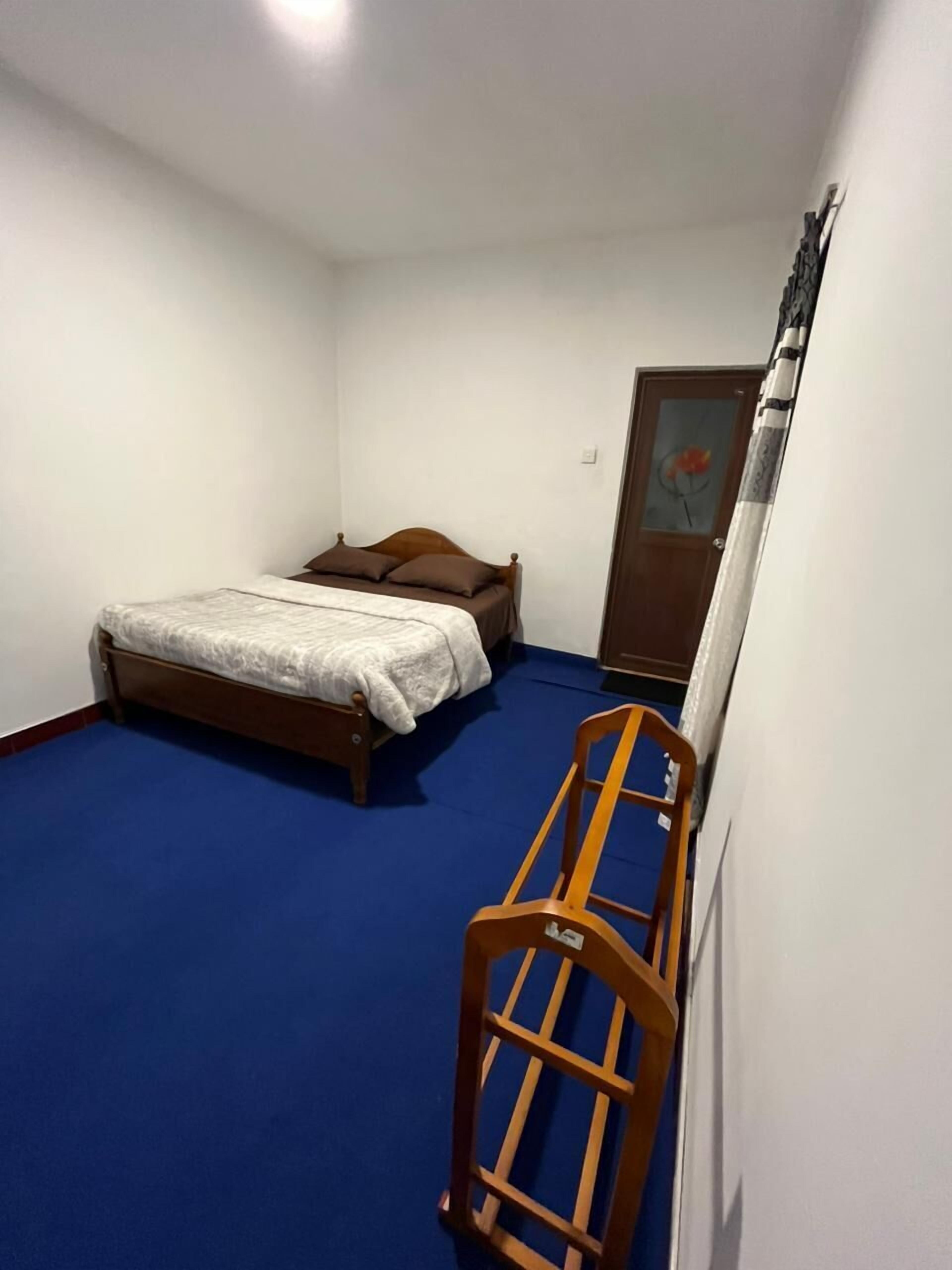 Ein kleines Schlafzimmer mit einem Bett, einem Holzstuhl und einer Tür mit einem Gemälde.