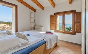 A bedroom with a bed, a window, a wooden ceiling, and a view of the outdoors. - Stunning Finca with Heated Pool for 8 Guests (Illes Balears)