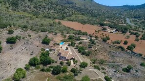 An aerial view of a rural area with scattered buildings, a swimming pool, and a winding road. - Stunning Finca with Heated Pool for 8 Guests (Illes Balears)