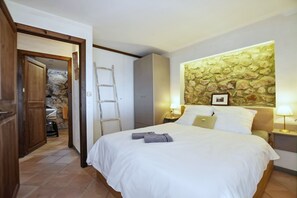 A bedroom with a bed, a wooden wardrobe, a stone wall, and a ladder. - Stunning Finca with Heated Pool for 8 Guests (Illes Balears)