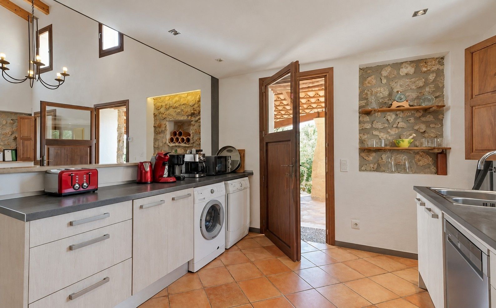A modern kitchen with a washing machine, a coffee maker, and a toaster.