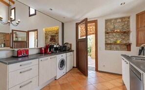 A modern kitchen with a washing machine, a coffee maker, and a toaster. - Stunning Finca with Heated Pool for 8 Guests (Illes Balears)