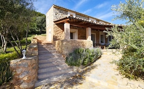 A stone building with a covered porch and steps leading to the entrance.