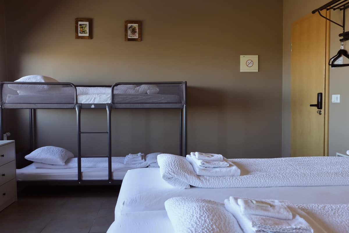 Une chambre d’hôtel avec des lits superposés, un lit simple et une armoire en bois.