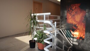 A staircase with a railing, a potted plant, and a wall with a fiery abstract painting. - Blue Viking Studios (Reykjanesbær)