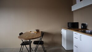 A compact kitchen with a wooden table, two chairs, a microwave, and a coffee maker. - Blue Viking Studios (Reykjanesbær)