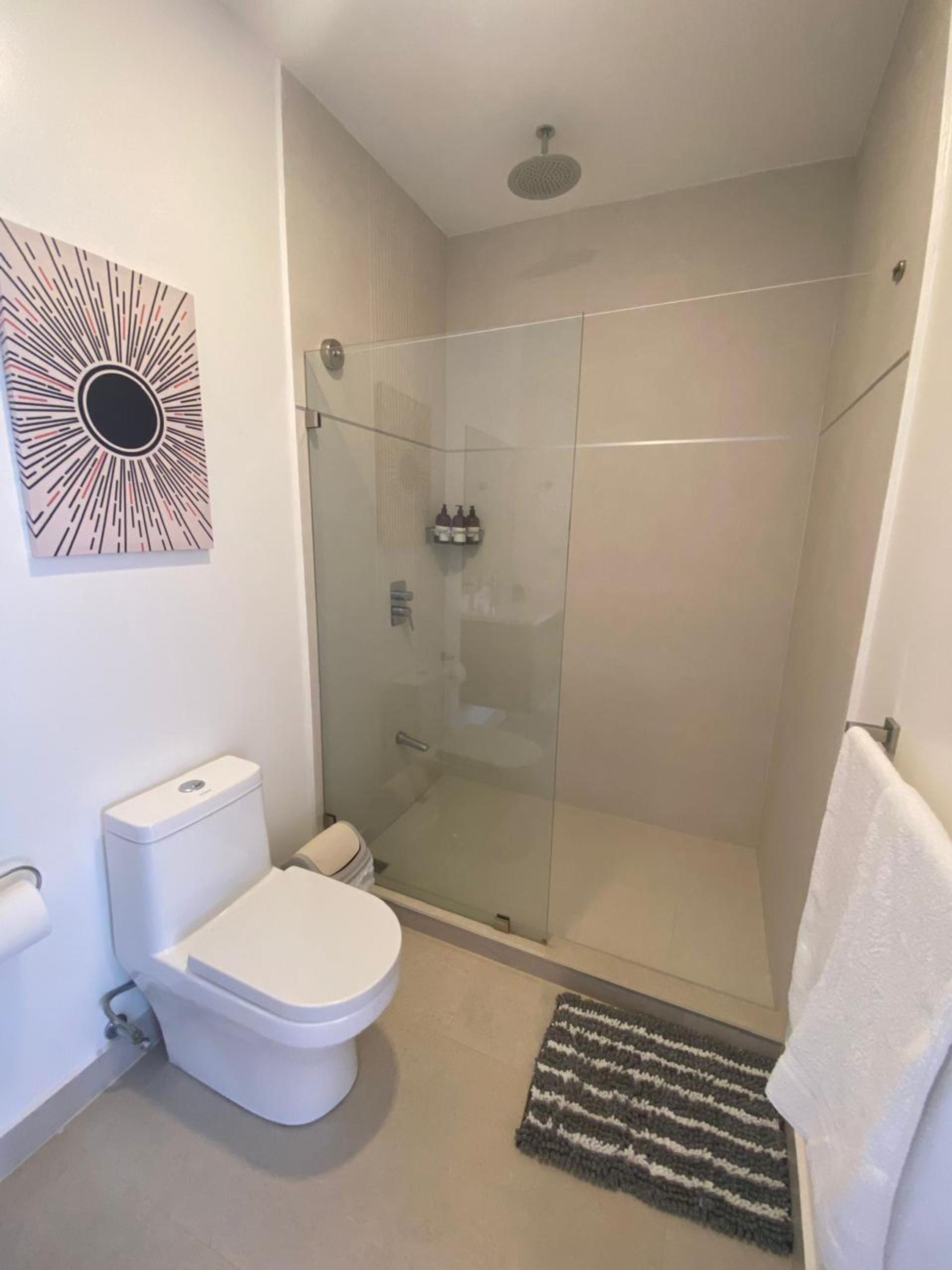 A modern bathroom with a glass-enclosed shower, a toilet, and a wall-mounted sink.