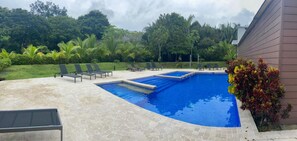 Une piscine avec des chaises longues et une terrasse en pierre.