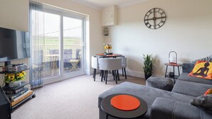 A modern living room with a grey sofa, a round table, and a large window. - Golygfa (Abergele)