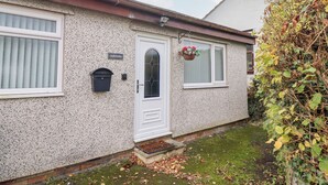 A house with a white door, a mailbox, and a window with a flower basket. - Golygfa (Abergele)