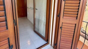 A room with a sliding glass door leading to a balcony, a tiled floor, and a visible door frame. - Casa Vacanza Gallura in Centro (San Teodoro)