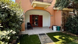 A two-story house with a balcony, a paved patio, and a well-maintained lawn. - Casa Vacanza Gallura in Centro (San Teodoro)