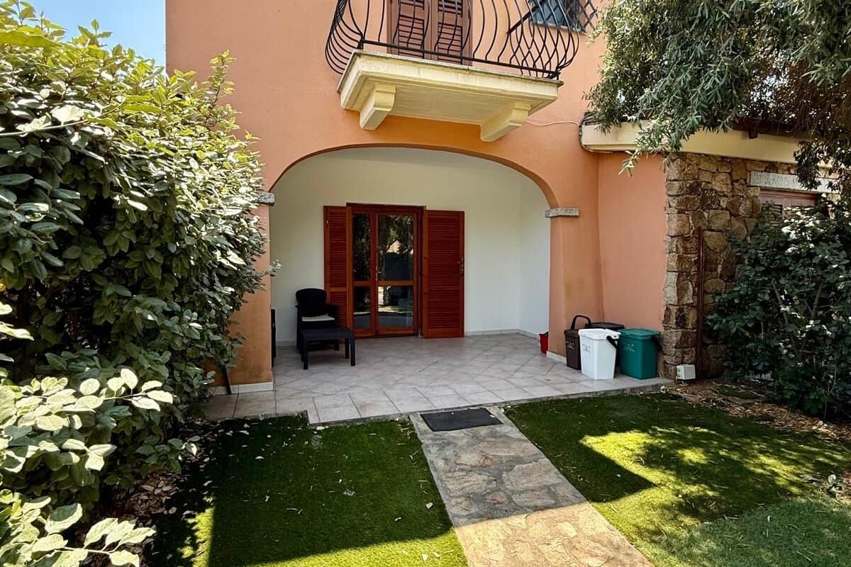 A two-story house with a balcony, a paved patio, and a well-maintained lawn.