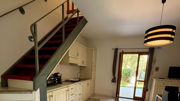 A spacious kitchen with a staircase leading to a dining area. - Casa Vacanza Gallura in Centro (San Teodoro)