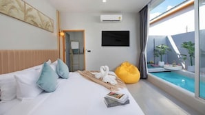 Ein modernes Hotelzimmer mit einem Bett, einem Flachbildfernseher, einer Klimaanlage, einem Fenster mit Blick auf einen Pool und einem gelben Sitzsack.