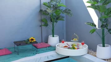 Um espaço ao ar livre pequeno e fechado, com área de estar, piscina pequena e plantas em vasos.