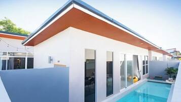 Uma casa moderna com piscina, janelas amplas e telhado de madeira.