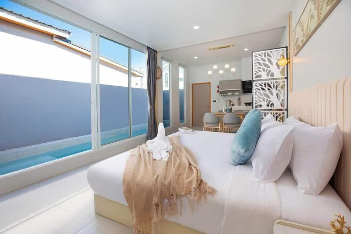 Een moderne hotelkamer met een groot bed, uitzicht op zee, een kitchenette en een eethoek.