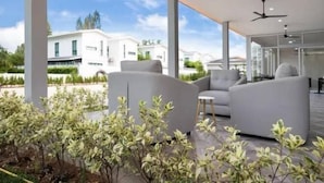 Ein moderner Außenbereich mit grauen Sofas und einer Glastrennwand.