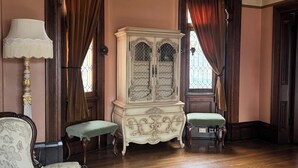 Une pièce comprenant un grand meuble richement décoré, deux bancs assortis, une lampe et une fenêtre avec des rideaux.
