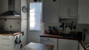 Een keuken met witte kasten, een fornuis, een spoelbak en een raam.