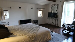 Een slaapkamer met een groot bed, een houten vloer, een spiegel, een stoel en decoratieve wandobjecten.