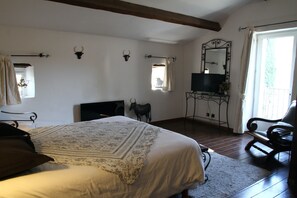 A bedroom with a large bed, a wooden floor, a mirror, a chair, and decorative wall-mounted items. - Mas de la Filoselle, vacation home for 14 people at the foot of the Cevennes mountains (Saint-Martin-de-Valgalgues)